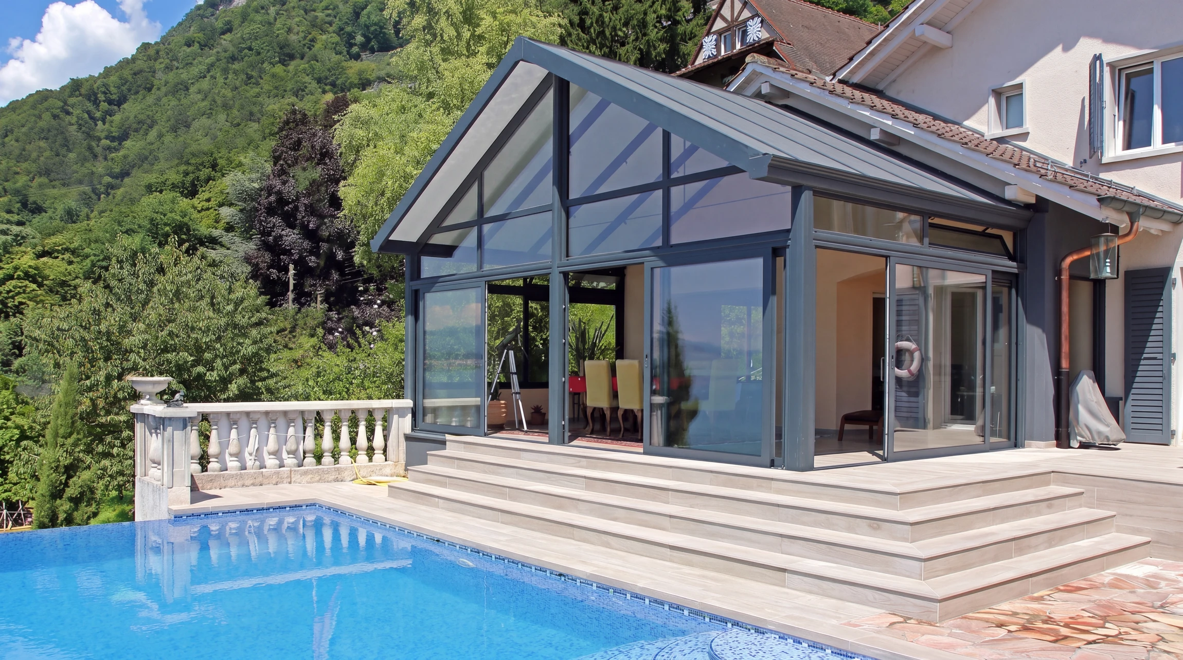 Véranda contemporaine à ossature aluminium anthracite, toiture mixte opaque/vitrage, adossée à une villa
