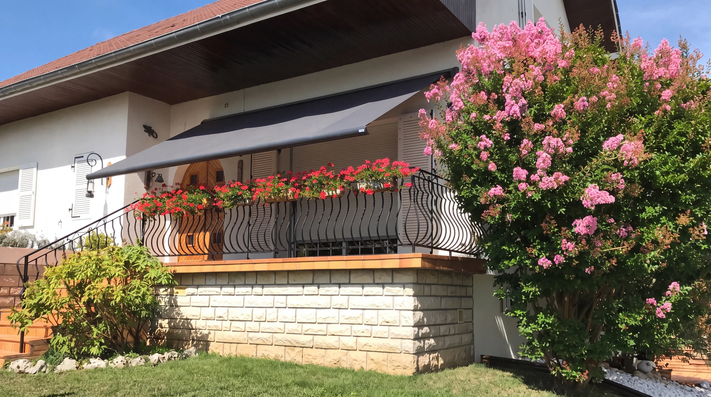 Store banne motorisé gris anthracite déployé sur une terrasse résidentielle surélevée