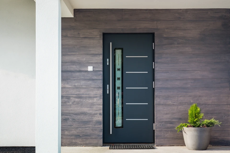 Entrée extérieure d'une maison avec une porte composite gris anthracite, encadrée dans une arche en plâtre texturé
