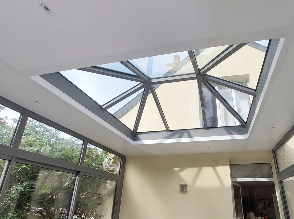 Véranda aluminium gris anthracite adossée à une maison plain-pied, toiture monopente avec faîtage décoratif