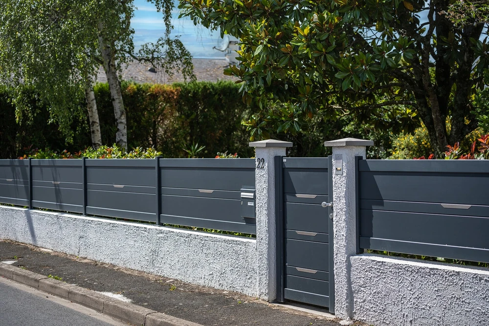 Entrée de propriété résidentielle avec portail battant double vantaux en aluminium gris anthracite, style arrondi en arc de cercle, lames verticales espacées