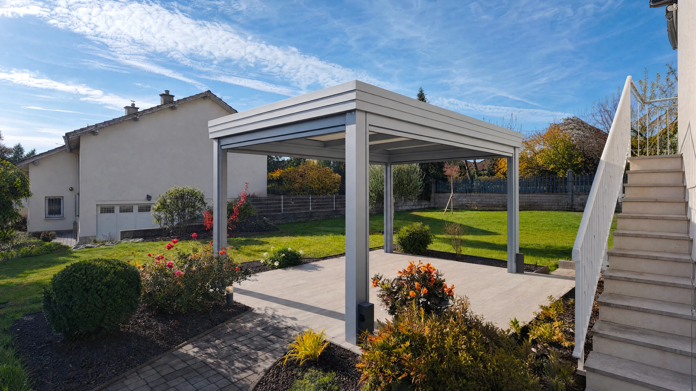 Volet coulissant en aluminium gris clair installé en façade extérieure d'une maison, partiellement ouvert devant une baie vitrée à deux vantaux avec rideau blanc