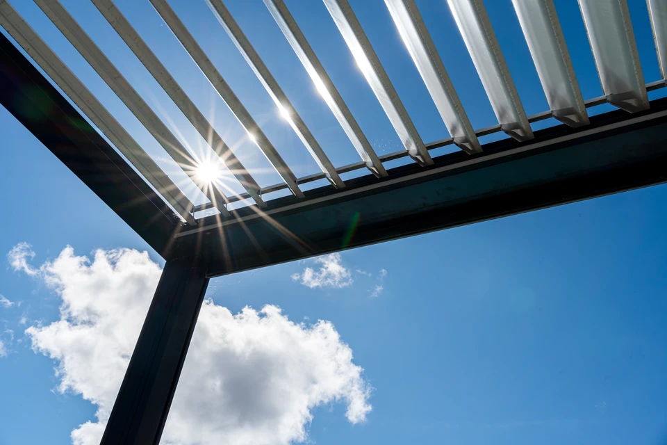 Pergola bioclimatique aluminium gris anthracite, structure autoportante à 4 poteaux carrés, toiture à lames orientables