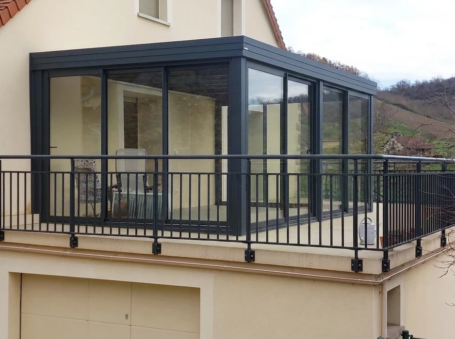 Véranda aluminium gris anthracite adossée à une maison plain-pied, toiture monopente avec faîtage décoratif