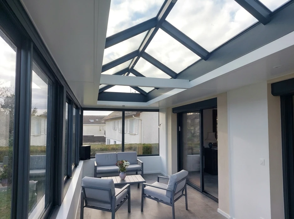 Véranda panoramique avec ossature aluminium anthracite et vitrage pleine hauteur sur trois côtés