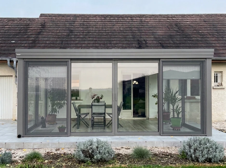 Véranda contemporaine en aluminium anthracite, installée en étage sur une terrasse bétonnée