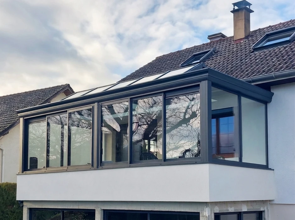 Véranda contemporaine en aluminium anthracite, installée en étage sur une terrasse bétonnée
