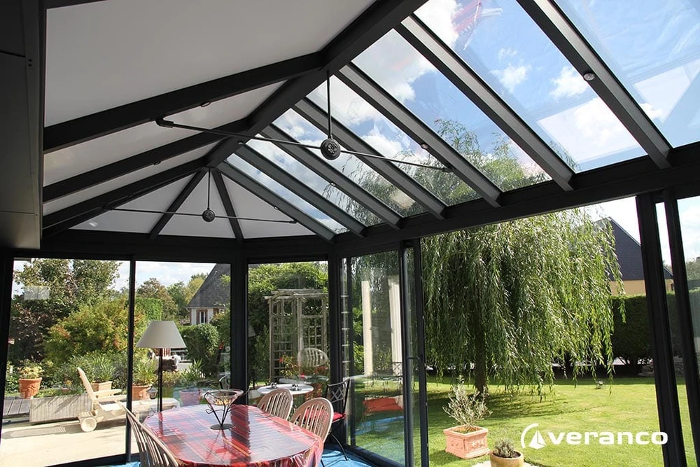 Véranda aluminium gris anthracite adossée à une maison plain-pied, toiture monopente avec faîtage décoratif